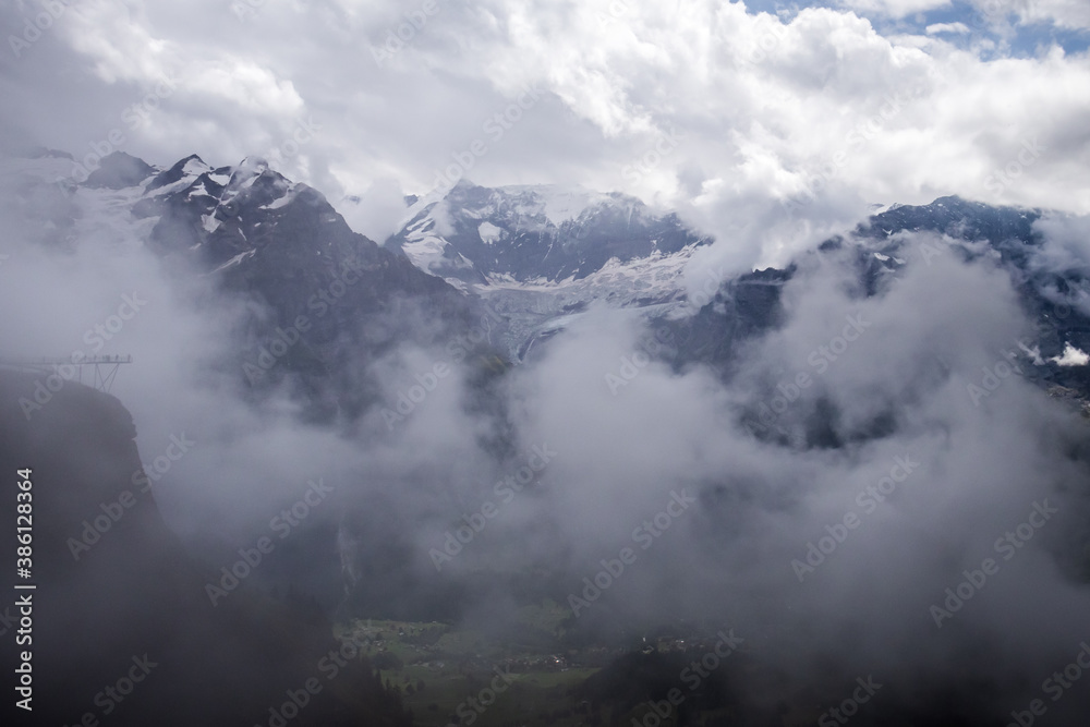 Mountains in the Valais Alps of Switzerland covered with fog on a summer day. 