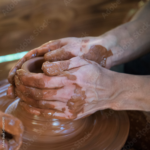 The Potter teaches the child to work on the Potter's wheel. Hands of people in close-up. Working with clay, handmade.