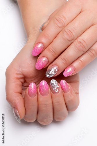 Gel nail design. Shiny pink, silver manicure with white lace, monograms, abstraction on short oval nails close-up on a white background	