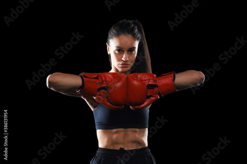 Modern with kickboxing woman in activewear and kickboxing gloves looking at you ready to fight on black background for healthy lifestyle design. Sport, healthy lifestyle. © ty
