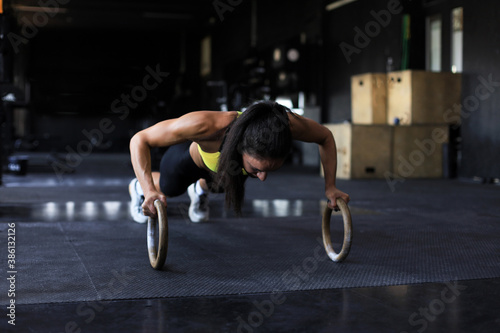 Sporty indian strong woman doing push-ups on rings.
