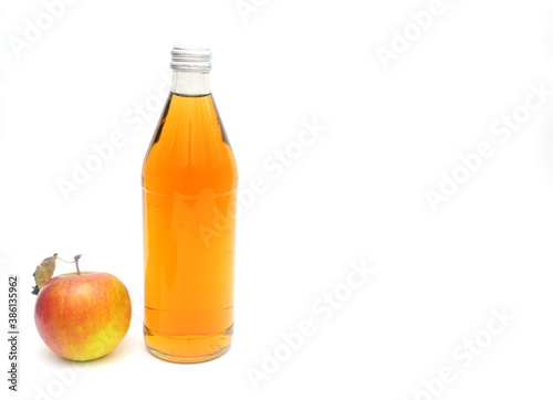 One whole apple with leaf and a bottle of apple cider vinegar on white background, copyspace.