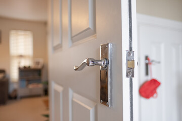 Shallow focus of an interior door handle seen on a fire door. The doorway leads to a living room of a  private house.
