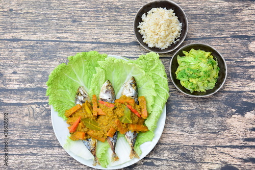 Pesmol Ikan Makarel (Indonesian food) or Mackerel fish with chili turmeric coconut milk sauce served with rice and sauteed napa cabbage photo