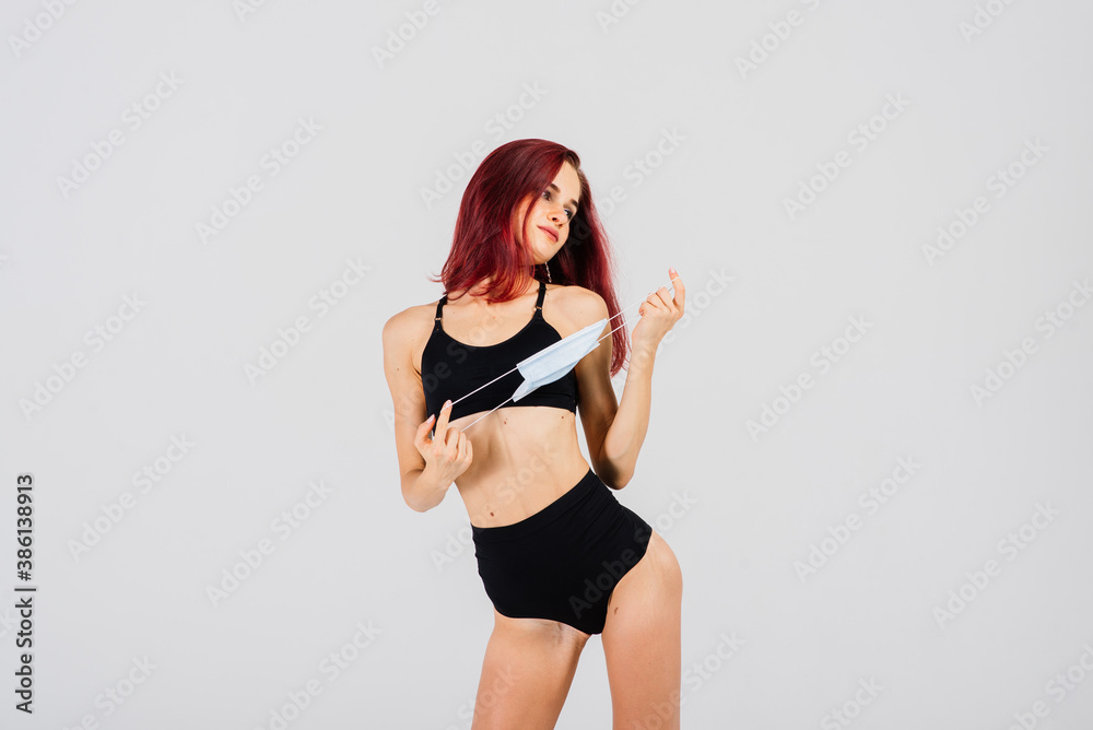Female dancer in the styles of strip-plastic and pole dance with face mask on light background.