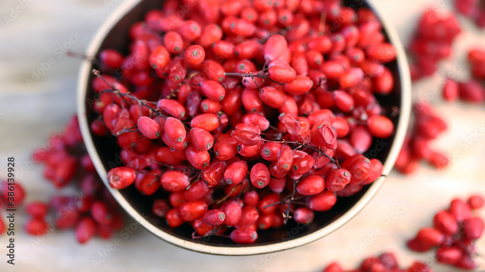 Berries and bunches of barberry in a bowl on a wooden surface. Barberry. Berries and bunches of barberry in a bowl on a wooden surface. Barberry.