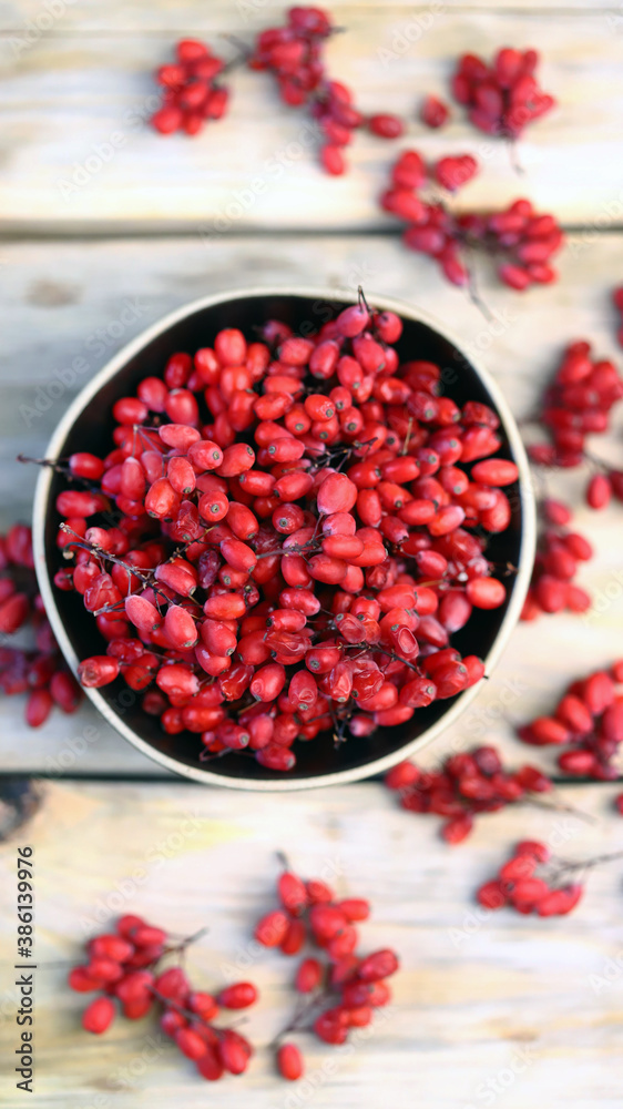 Berries and bunches of barberry in a bowl on a wooden surface. Barberry. Berries and bunches of barberry in a bowl on a wooden surface. Barberry.