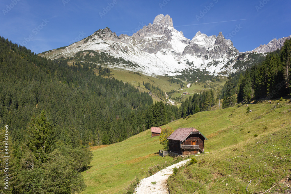 Picturesque alpine landscape with the 'Bishop's mitre' mountain covered in snow and alpine meadow with log cabin