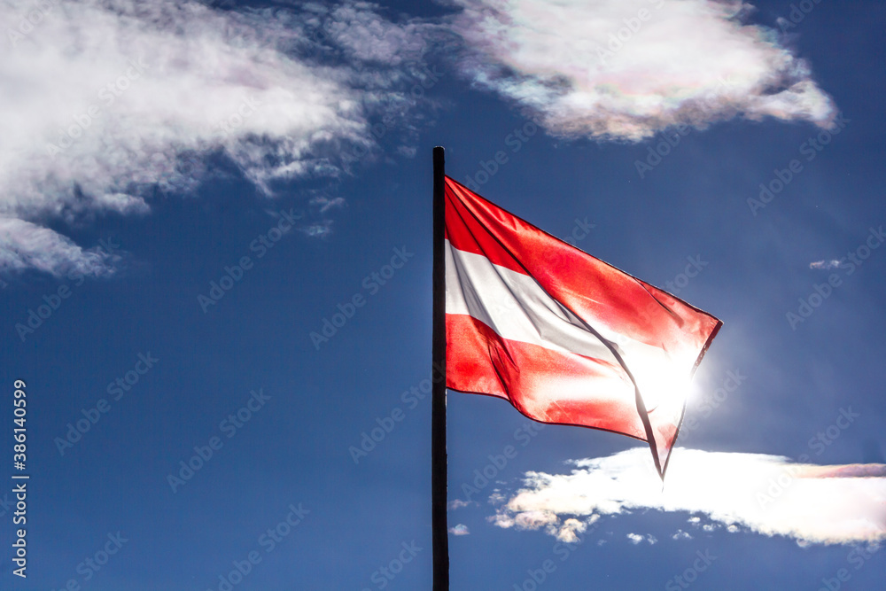 Waving flag of Austria backlit by the sun and with blue sky in the background