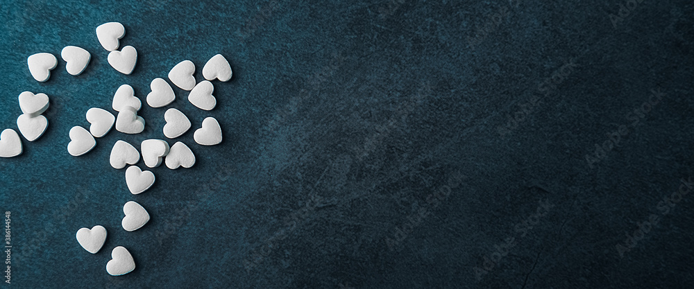 White medical pills in the form of hearts on a blue background. White medical pills in the form of hearts on a blue background.