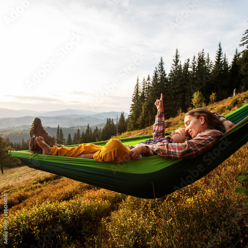 Boy tourist resting in a hammock in the mountains at sunset