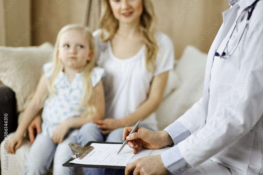 Obraz premium Doctor and patient. Pediatrician using clipboard while examining little girl with her mother at home. Sick and unhappy child at medical exam. Medicine concept