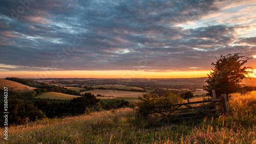 a wooden gate on a hill in the english countryside at sunset