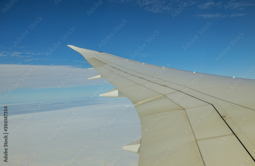 Fototapeta premium Clouds and sky as seen on a wing of an airplane flying