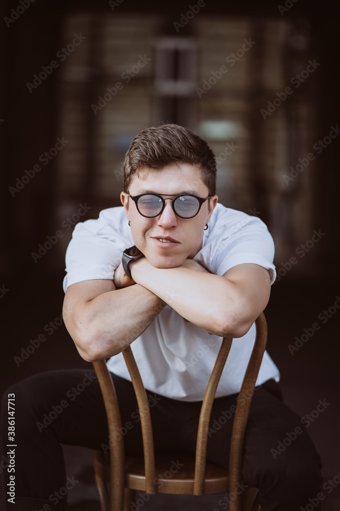 portrait of men sitting on chair with white t-shirt and sunglasses in the street