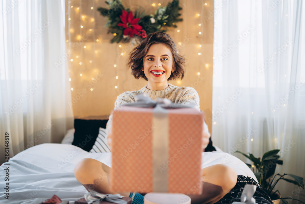 Happy and pretty brunette on the bed with gift boxes around her.