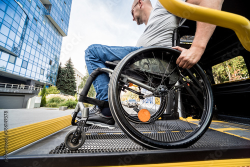 A man in a wheelchair on a lift of a vehicle for people with disabilities