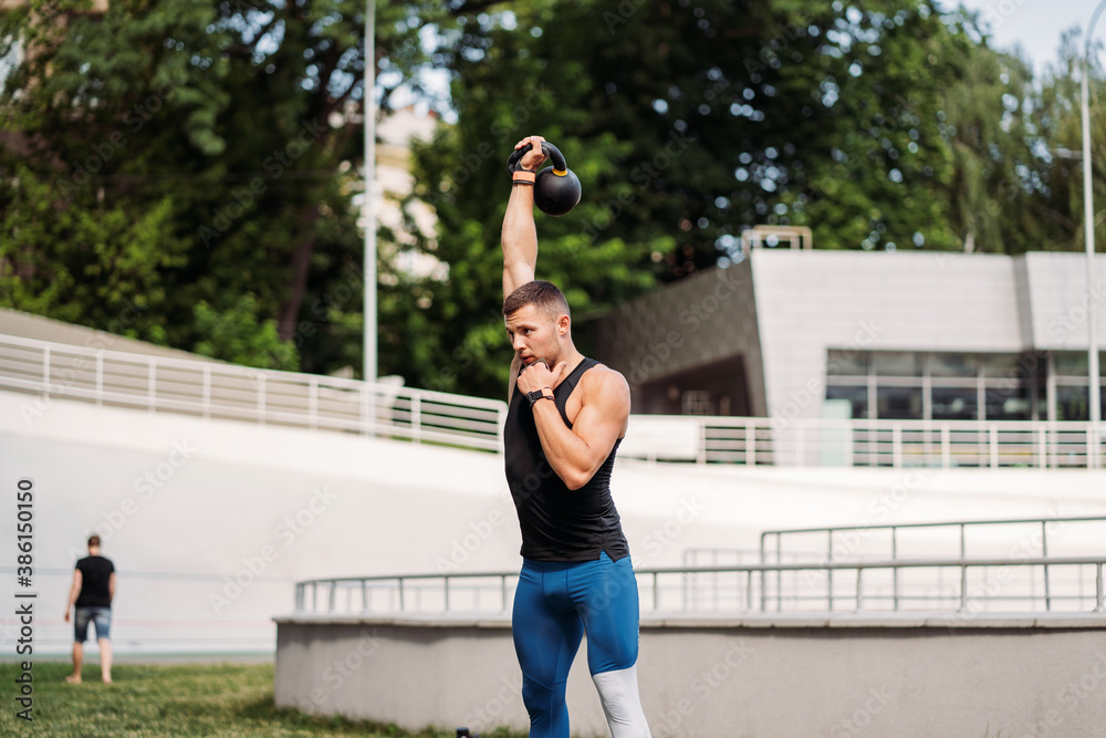 Sportive guy training with kettlebell. Strength and motivation.