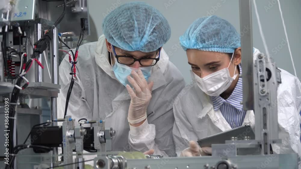 Group of engineer worker wearing ppe suite and face protective medical mask , glove useing digital tablet analyze  operation and check quality of mask manufacturing machine at lab in industry factory