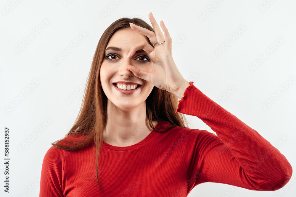 Image of pretty woman 20s laughing and looking at you through hole made by fingers. Human emotions concept Image of pretty woman 20s laughing and looking at you through hole made by fingers. Human emotions concept