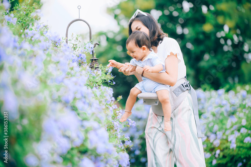 mother with little child in white blooming garden. woman with son in green leaves happy family outdoors in spring