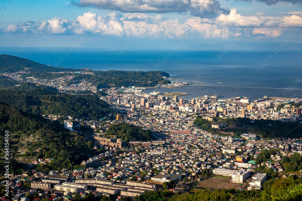 天狗山山頂から見える、小樽の市街地とその奥にある石狩湾、雲の浮かぶ青空