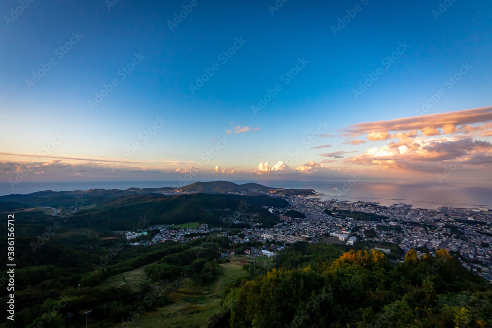 天狗山の展望台から眺める小樽の市街地と、夕焼け空に浮かぶ雲と石狩湾