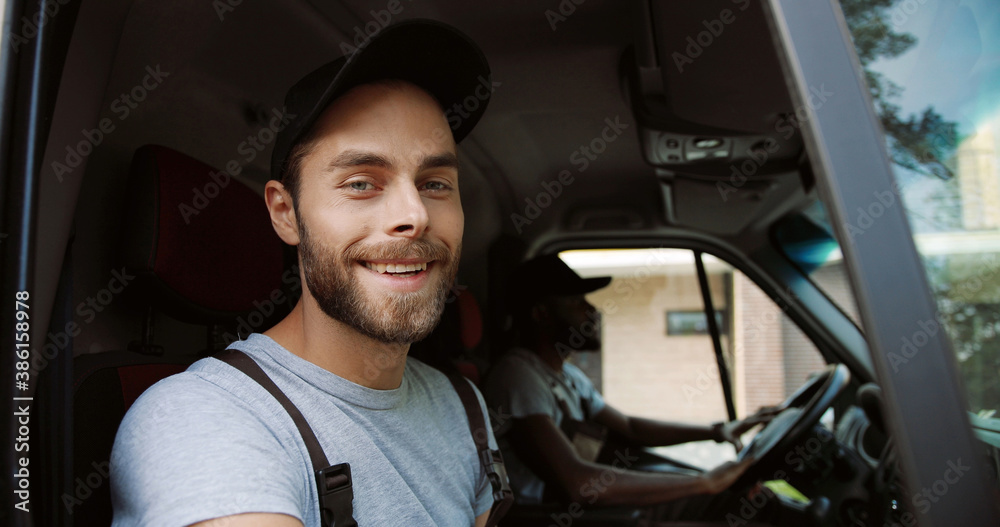 Close up portrait of two smiling delivery men in uniform sitting in delivery van. Close up portrait of two smiling delivery men in uniform sitting in delivery van.