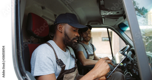 Couriers. Two delivery men reading addresses sitting in delivery van. photo