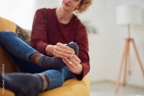 Foto Woman with feet intense pain sitting on a couch at home.
