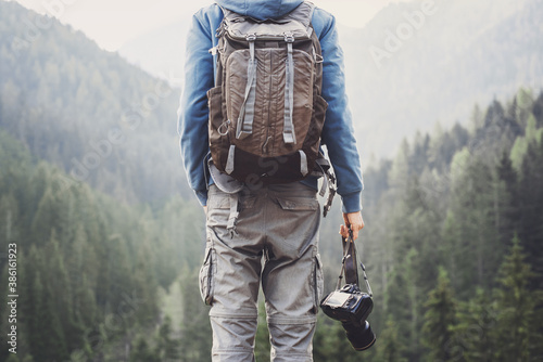 Young cheerful man photographer taking photographs with digital camera in a mountains, Travel and active lifestyle concept	 photo