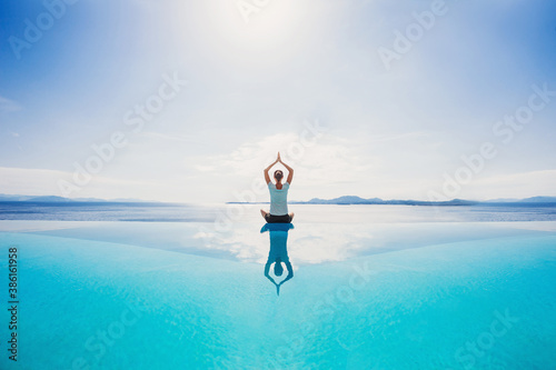 Fototapeta Naklejka Na Ścianę i Meble -  Young woman practicing yoga by the sea. Harmony, meditation, healthy lifestyle and travel concept. 
