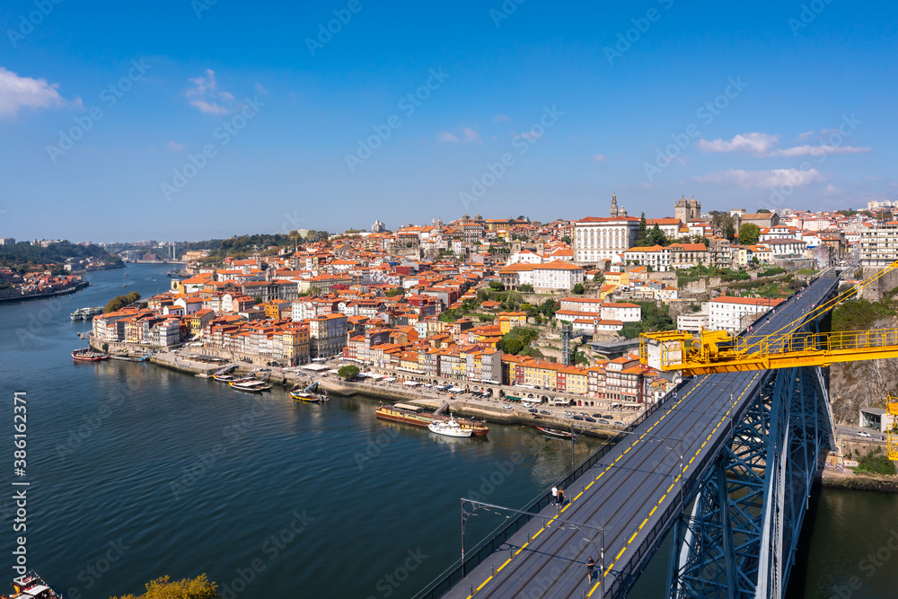 Panoramic top view of the Bridge of Luis 1. the banks of the Douro river in the city of Porto. Hill descending to the water with colorful houses. Lots of cafes on the waterfront and traditional boats.