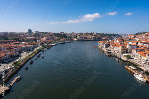 Beautiful view of the banks of the Douro river in the city of Porto. A hill descending to the water with many colorful houses. Lots of cafes on the waterfront and wooden traditional boats at the pier.