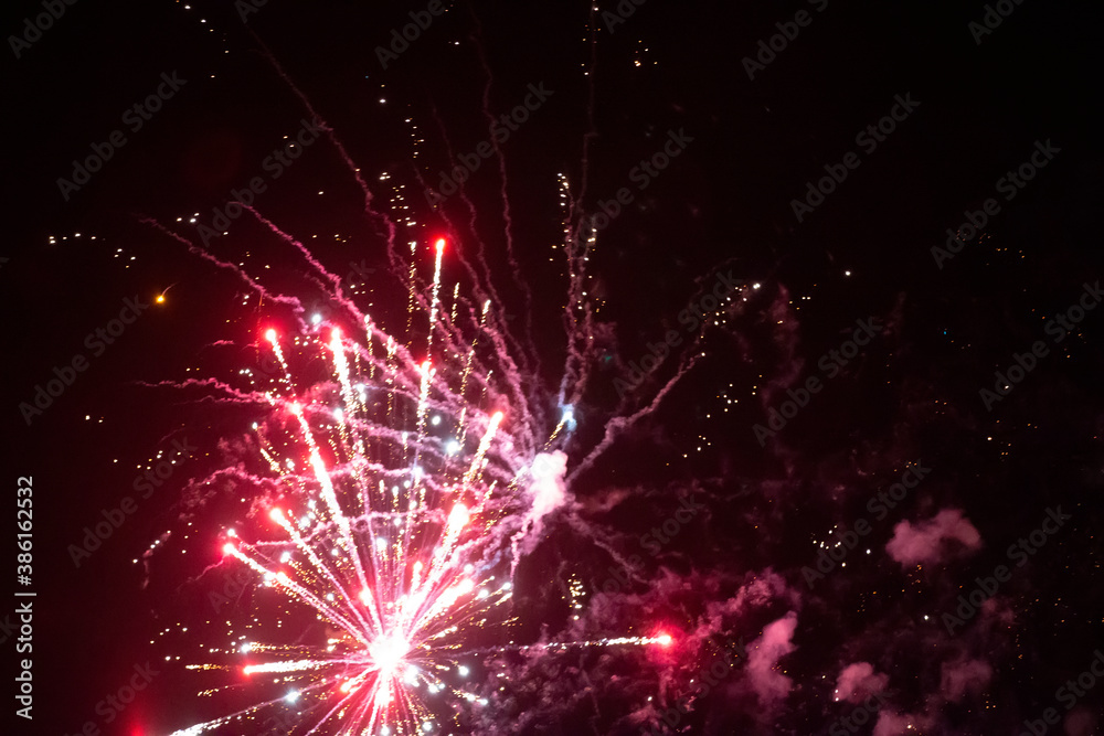 Fototapeta premium On a black background, red rays and sparks of a scattering fireworks with smoke.