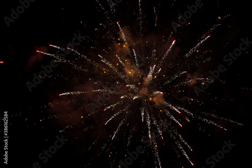 On a black background, golden rays and sparks of scattering fireworks.