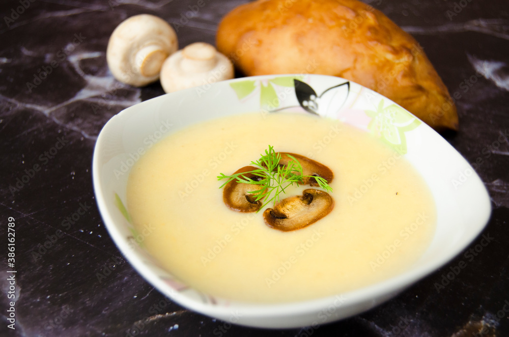 Mushroom cream soup close-up. Champignon soup puree, pie and champignon on a dark granite background. Tasty winter vegetarian food. Mushroom cream soup close-up. Champignon soup puree, pie and champignon on a dark granite background. Tasty winter vegetarian food.
