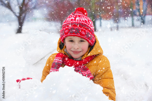 Child in winter. A happy boy in bright clothes plays in the snow.