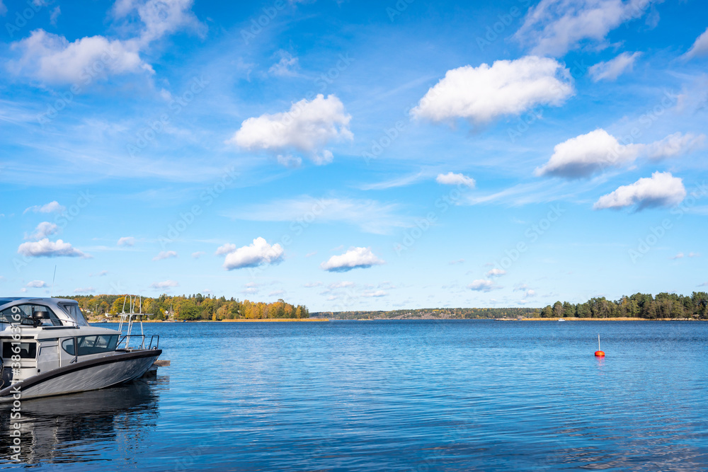 Autumn landscape of the coast of Sweden. Forest islands with colorful trees in the gulf of the Baltic Sea. The yacht boat moored to the shore. Panoramic view of Scandinavia in an autumn day.