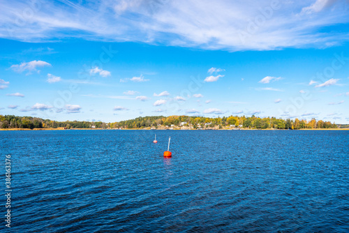 Autumn landscape of the coast of Sweden. Forest islands with colorful trees in the gulf of the Baltic Sea. Panoramic view of Scandinavia in an autumn. Bright red buoys float on the surface of water.