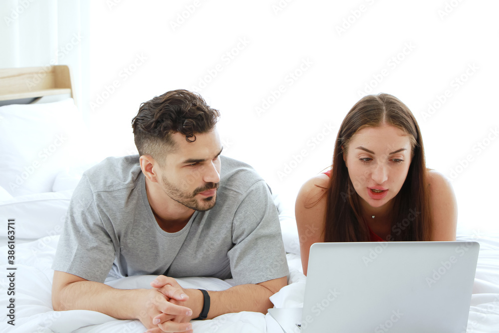 Young Caucasian couple love is relaxing with laptop in social media for shopping online in bedroom. Technology for Married family lifestyle on holiday Concept. Young Caucasian couple love is relaxing with laptop in social media for shopping online in bedroom. Technology for Married family lifestyle on holiday Concept.