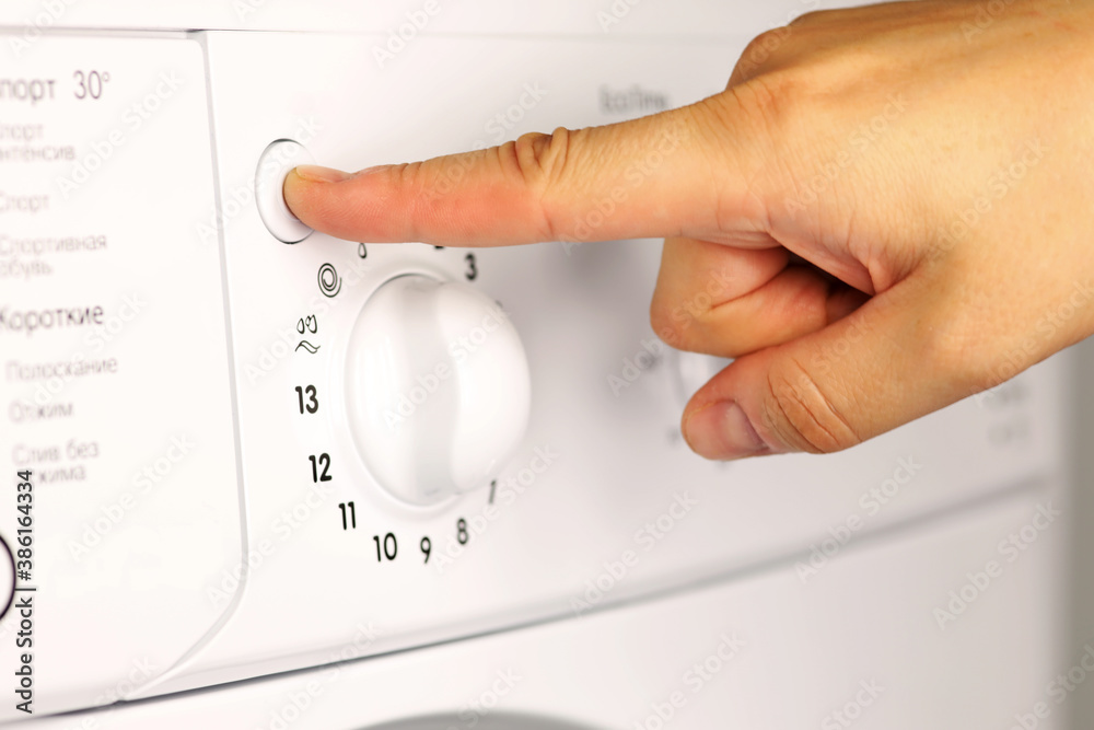 Girl's hand presses the Start button on the control panel of the washing machine close-up Girl's hand presses the Start button on the control panel of the washing machine close-up