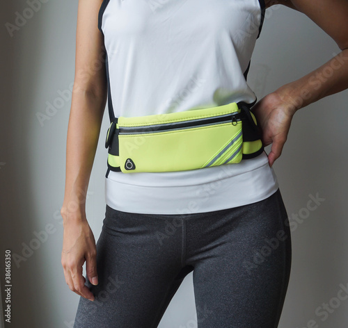 Woman wearing white t-shirt and yellow waist bag for exercising.