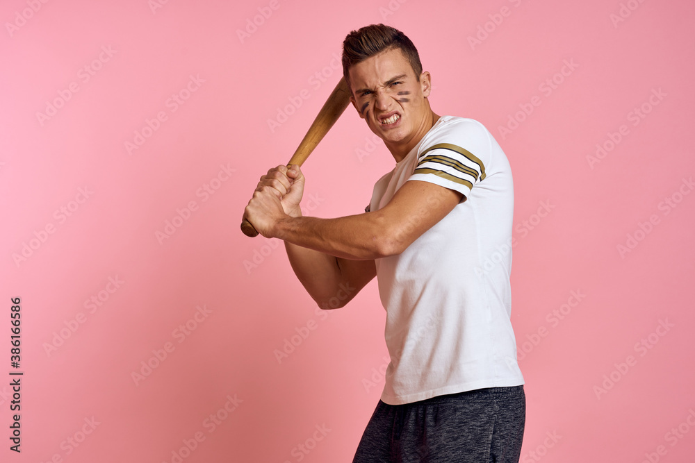 Energetic man with a bat on a pink background T-shirt face make-up black lines aggression model Energetic man with a bat on a pink background T-shirt face make-up black lines aggression model