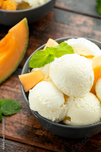 Melon ice cream with mint in bowl on wooden table