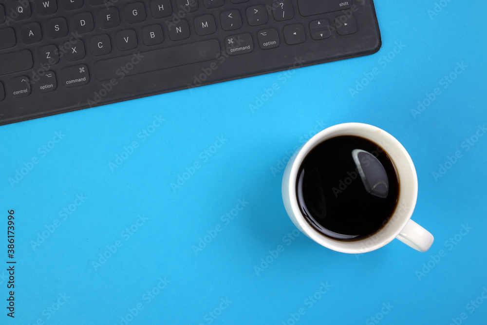 Black computer keyboard coffee cup on blue white background top view copy text space