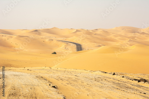 An empty asphalt road zigzagging through the desert and sand dunes in the United Arab Emirates