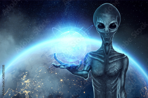 A gray alien, humonoid, holds a hologram of the globe on his hand. UFO concept, aliens, contact with extraterrestrial civilization