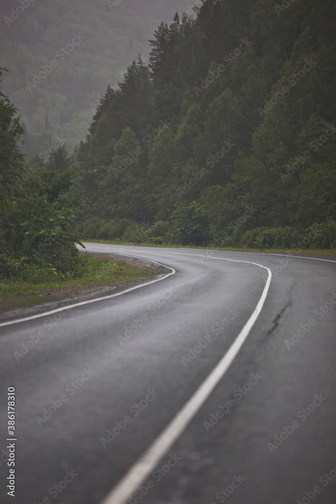 Fototapeta premium Asphalt road through the mountains forest in rainy season