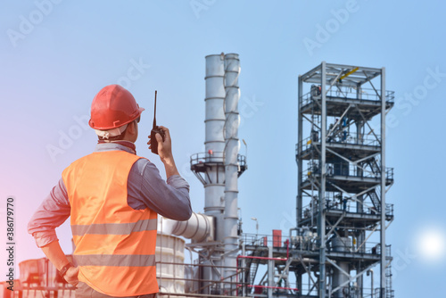Supervisor standing in factory of Oil Refinery plant or power plant operated by hand holding walkie- talkie for control working. © TawanSaklay